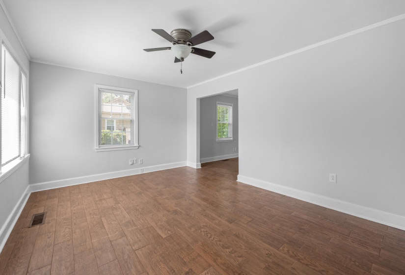 Spacious room featuring wood-finish flooring, light gray walls, white trim, and a ceiling fan