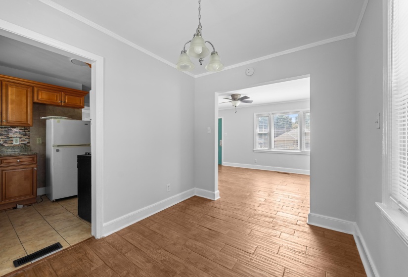 Open concept dining area featuring wood-finish flooring, a three-light chandelier, and access to the kitchen and living space