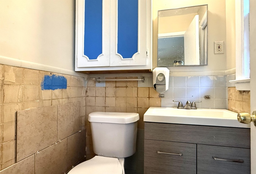 Bathroom featuring a gray wood-finish vanity with an integrated sink, a two-handle chrome faucet, and a wall-mounted mirror
