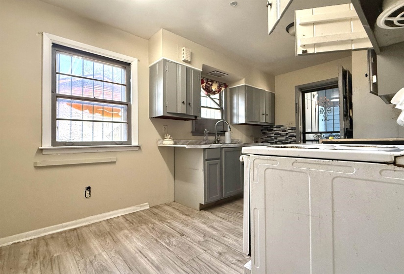 Kitchen featuring wood-finish flooring, gray cabinetry, a mosaic tile backsplash, and a stainless steel sink with a gooseneck faucet
