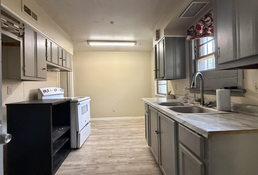 Kitchen featuring wood-finish flooring, dual-basin stainless steel sink, painted cabinetry, and a freestanding electric range