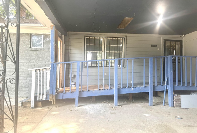 Exterior featuring a covered porch with a ramp entry, grey horizontal siding, and a security screen door