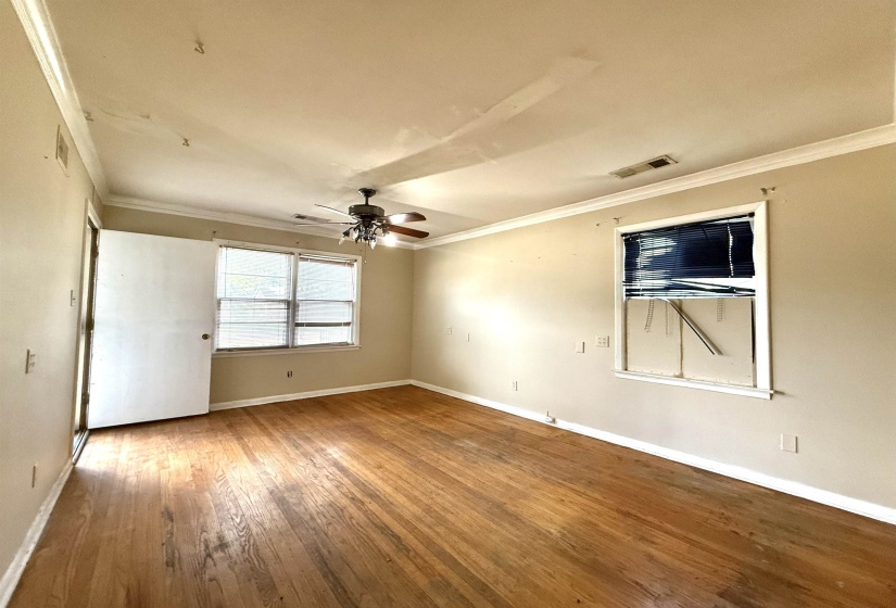 Interior space featuring wood-finish flooring, a ceiling fan, and crown molding