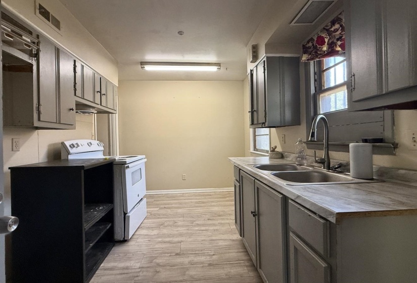 Kitchen featuring wood-finish flooring, two windows, painted cabinetry, a double basin sink with a high-arc faucet, and an electric range