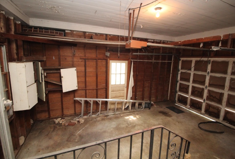 Garage space featuring exposed wall studs, an overhead garage door, and a concrete floor