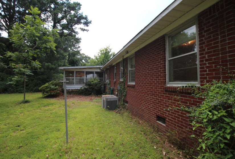 Brick exterior with multiple windows, a screened-in porch, and a grassy yard