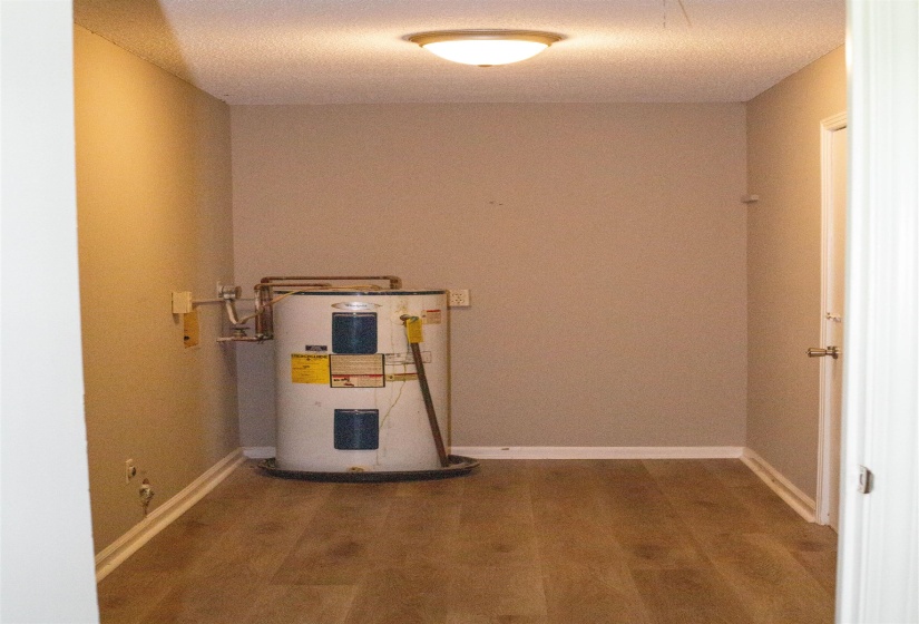 Utility area featuring wood-finish flooring, light tan wall paint, and white baseboards