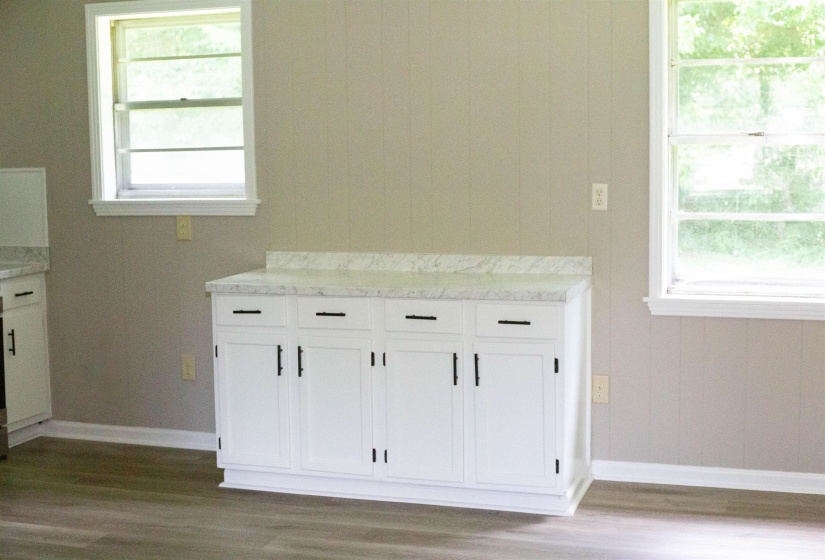 White cabinetry featuring black hardware and a light-toned countertop