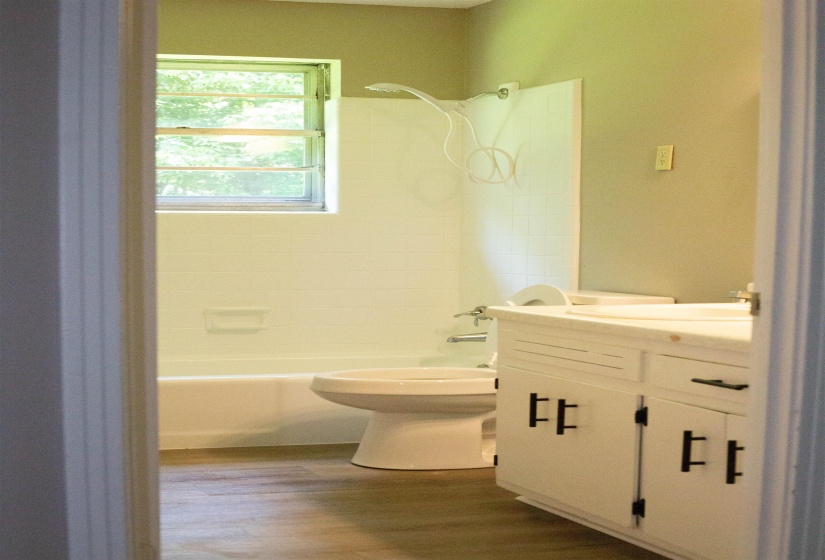 Bathroom featuring a white bathtub, toilet, and vanity with dual sinks