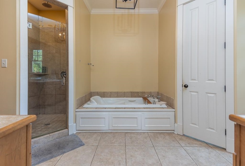 Bathroom featuring a spacious walk-in shower with tile surround and glass enclosure, an integrated soaking tub with a tiled deck, and light-toned floor tiling
