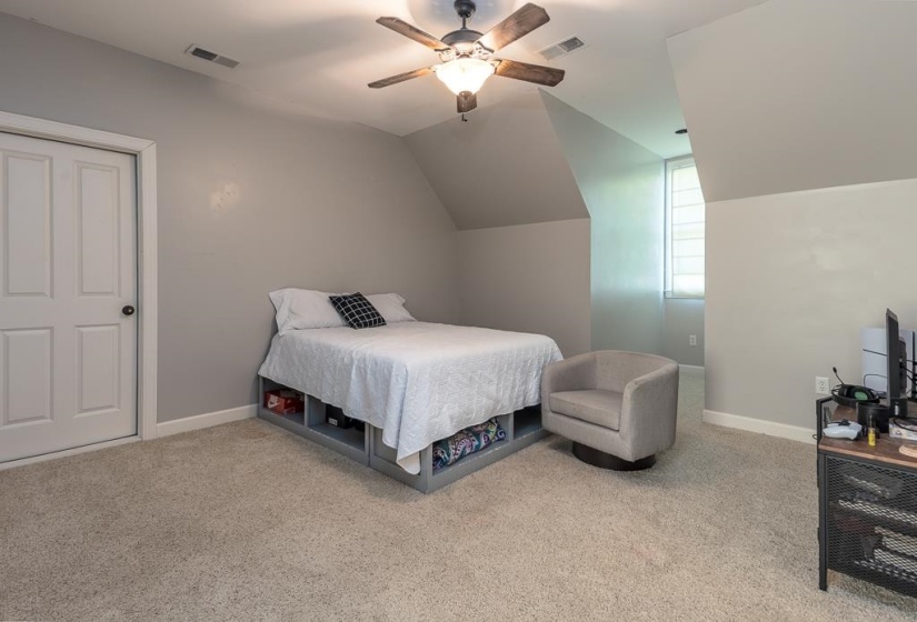 Carpeted room featuring a ceiling fan with light fixture, neutral wall paint, and a white paneled door