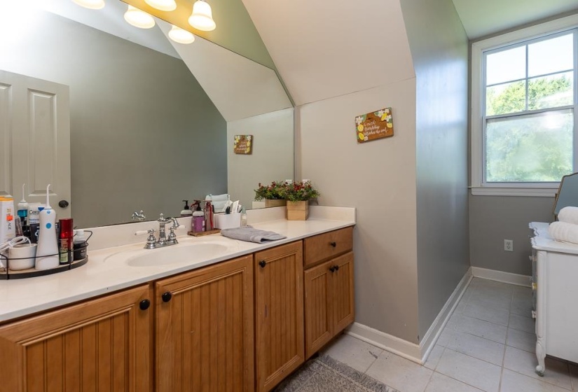 Bathroom vanity featuring a single sink, light-toned countertop, and wood-panel cabinetry