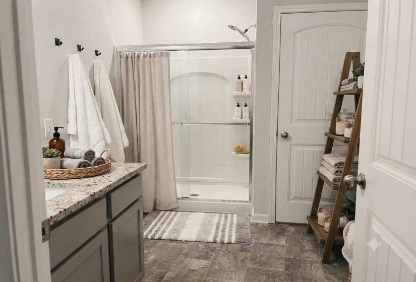 Bathroom featuring a granite-look countertop, a built-in shower stall with glass doors, and durable tile flooring