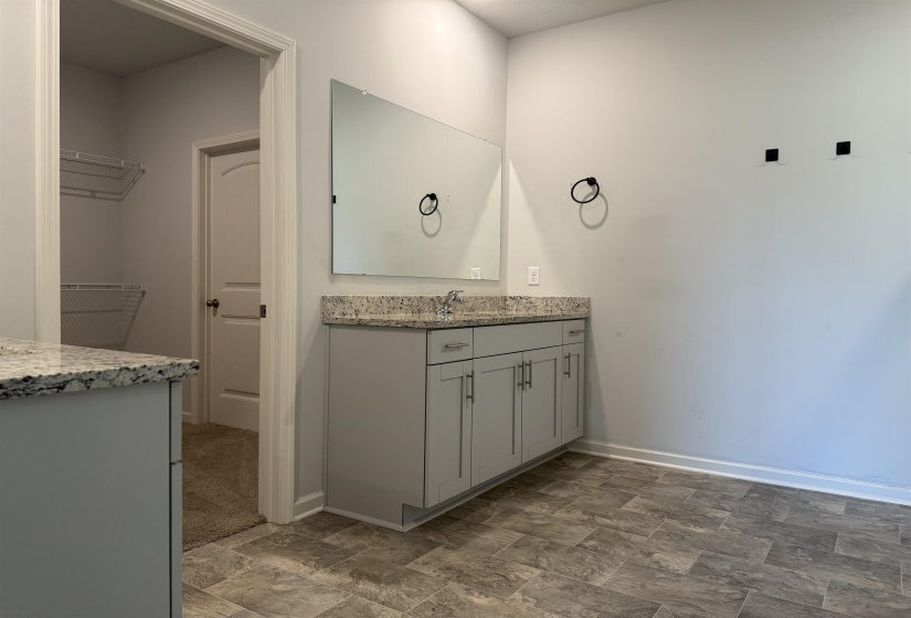 Bathroom vanity featuring a light gray cabinet base, speckled stone countertop, and a rectangular mirror