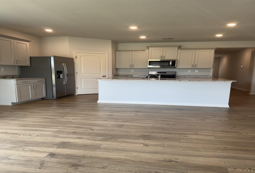 Kitchen featuring a central island with countertop seating, light wood-finish flooring, recessed lighting, stainless steel appliances, and light-toned cabinetry with coordinating countertops