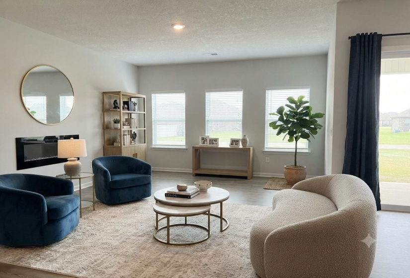Spacious living area featuring multiple windows with blinds, wood-finish flooring, and a built-in electric fireplace