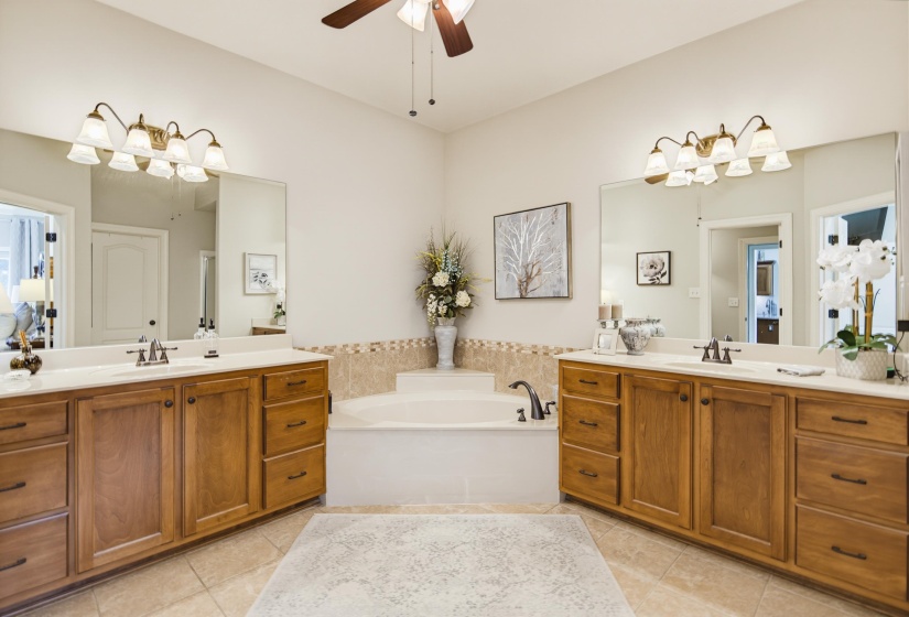 Dual vanities with integrated sinks, each featuring oil rubbed bronze faucets and fixtures with  expansive mirrors and deep tub.