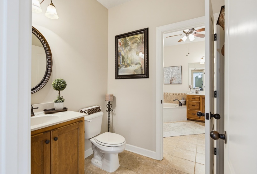 Primary bathroom toilet area with separate vanity located just off larger primary bathroom and separate access from garage entry way off kitchen area