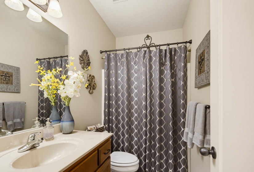 Bathroom with a single vanity featuring a built-in sink, chrome faucet, and wood-finish cabinetry. Linen closet located behind door.