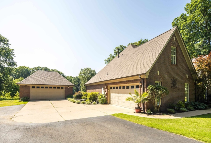 Property features plenty of parking due to large concrete and paved driveway area between a side entry 2 car garage and a detached 2 car garage.