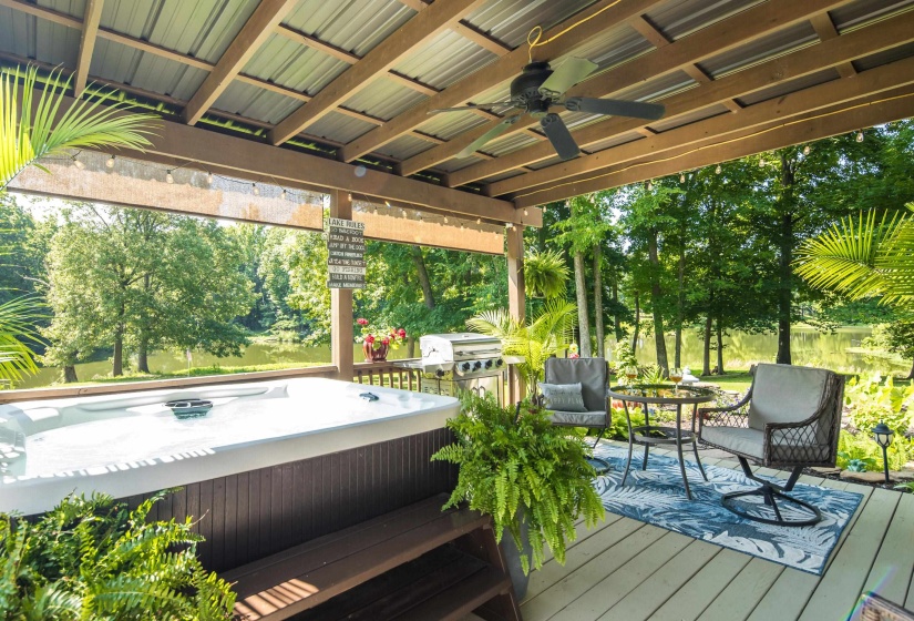Covered outdoor deck with hot tub perfect for enjoying lake view while grilling