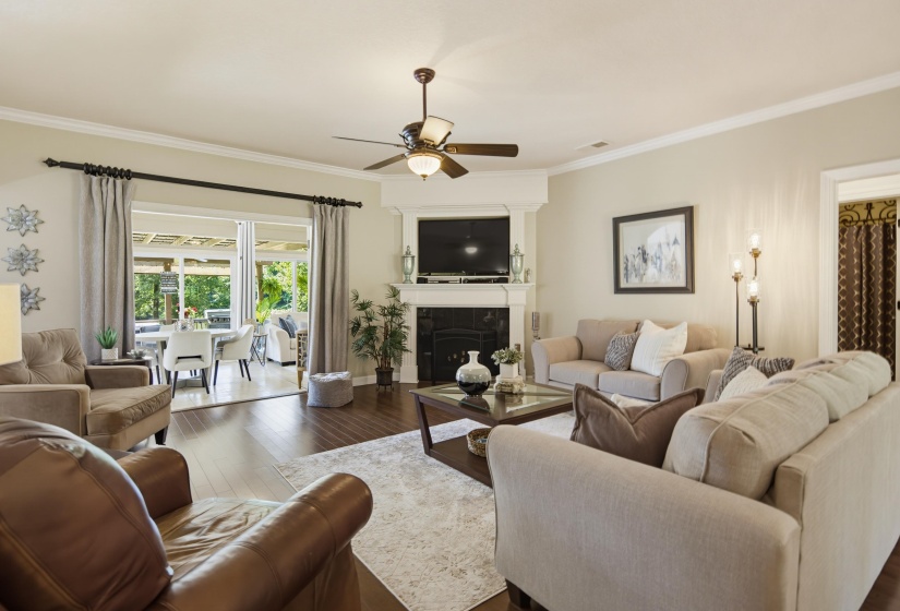 Spacious living area featuring wood-finished floors a gas fireplace and  French style doors which open to sunroom.