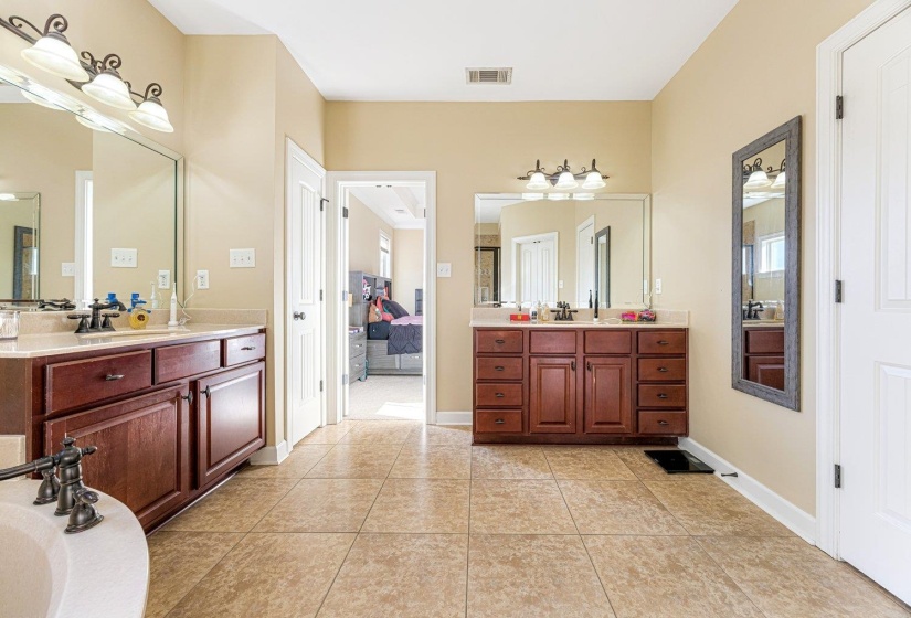 Spacious bathroom featuring twin vanity sinks with dark wood cabinetry and light-toned countertops