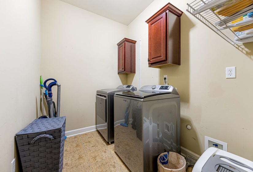 Dedicated laundry room featuring two wall-mounted wood-finish cabinetry, a white wire shelving unit, and linoleum flooring