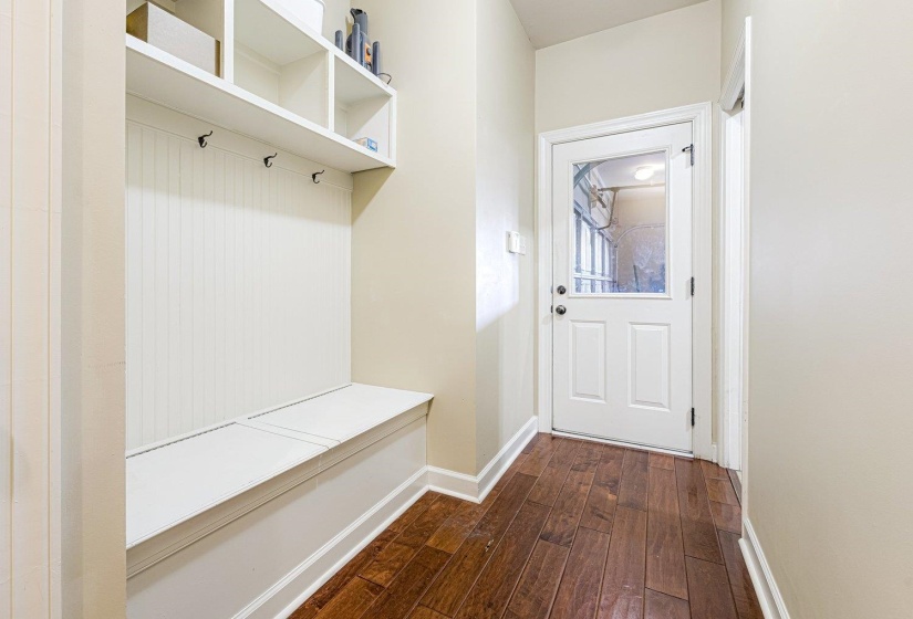 Entryway mudroom with built-in bench seating, overhead shelving, and wall hooks