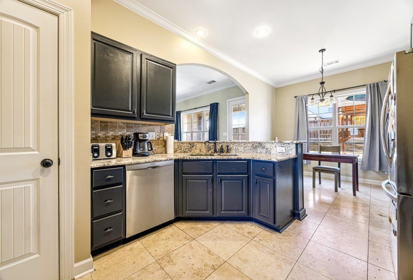 Kitchen featuring dark cabinetry, stainless steel appliances, granite countertops, and a tiled backsplash