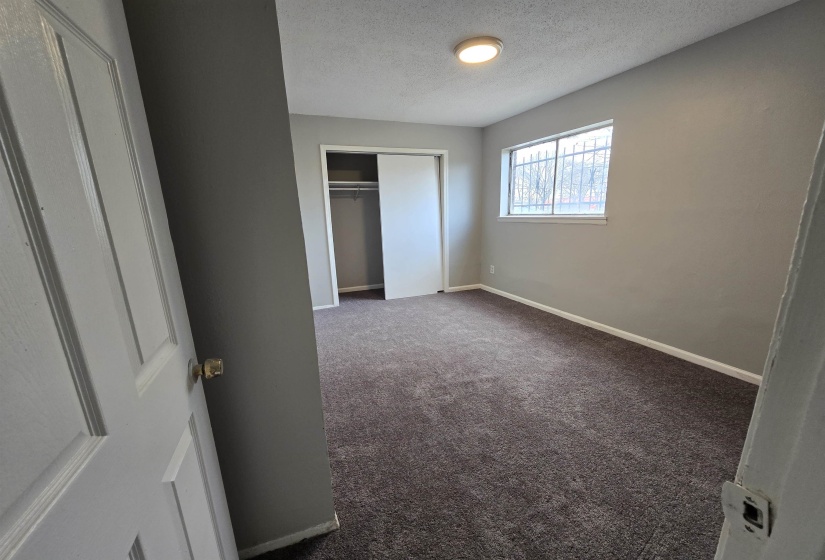 Unfurnished bedroom with a textured ceiling, dark carpet, and a closet