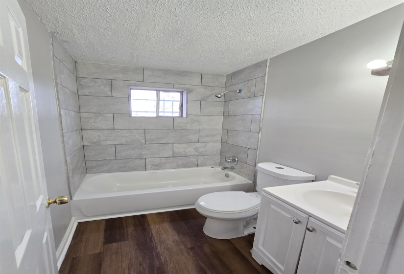 Full bath featuring vanity, bathtub / shower combination, dark wood-type flooring, and a textured ceiling