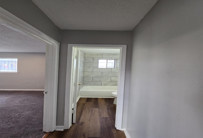 Full bathroom with a textured ceiling, dark wood finished floors, and dark carpet
