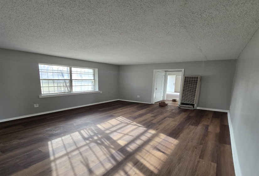 Unfurnished room with a heating unit, a textured ceiling, and dark wood finished floors