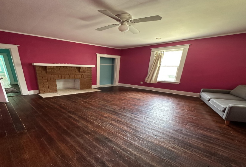 Living space featuring wood-finish flooring, a brick fireplace, and a ceiling fan