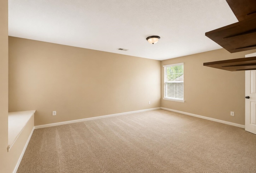 Spacious bedroom featuring neutral carpeting, a large window with blinds, and light-toned walls