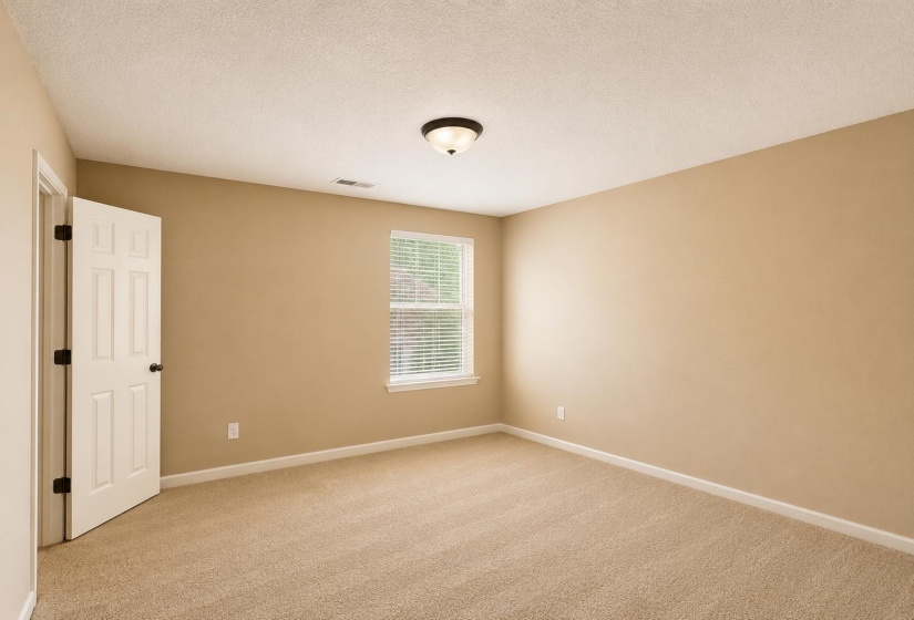 Carpeted bedroom with neutral wall tones and white baseboards