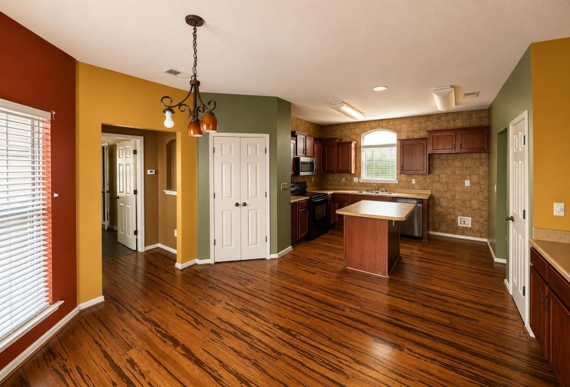 Open concept kitchen and dining area featuring wood-finish flooring, a kitchen island with counter seating, dark wood cabinetry, and a double-door closet