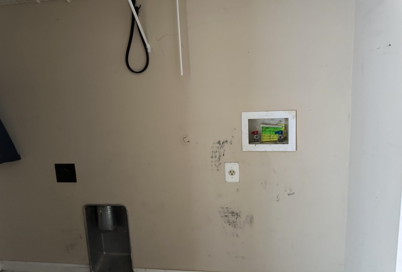 Utility area featuring a wall-mounted washing machine hookup, a dryer vent opening, an electrical outlet, and a utility sink drain