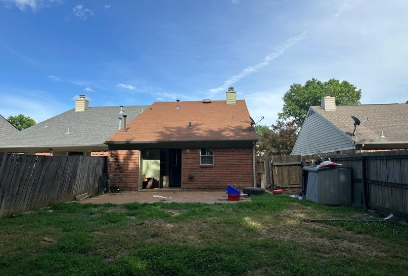 Expansive backyard with a brick exterior, a sliding glass door, and a single window
