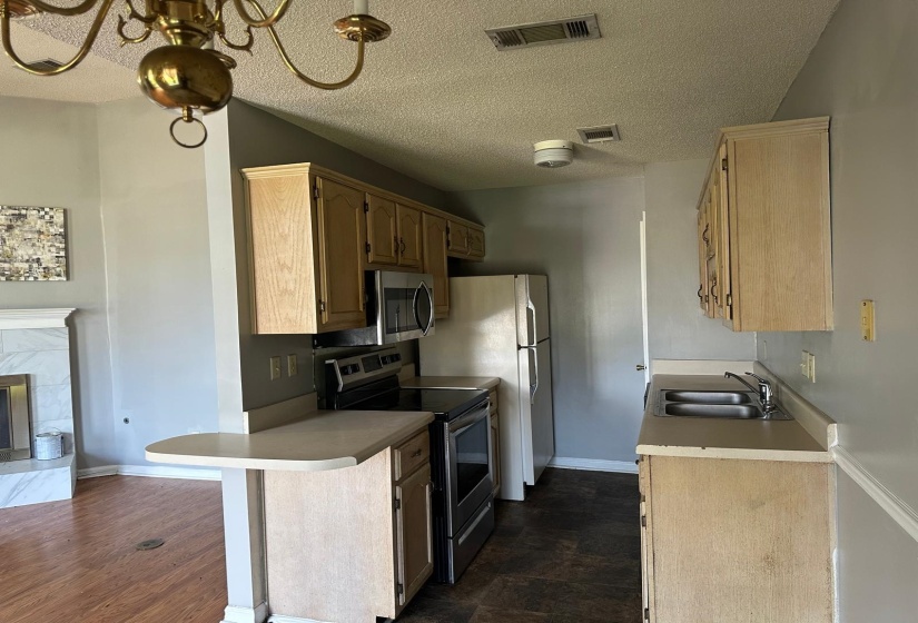 Functional kitchen featuring light wood cabinetry, stainless steel microwave, and dual basin sink