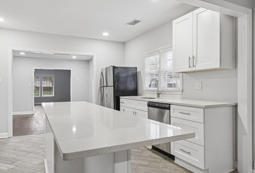 Kitchen featuring white cabinetry, wood finish floors, a kitchen island, light stone counters, and recessed lighting