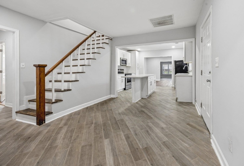 Unfurnished living room featuring stairs and light wood finished floors