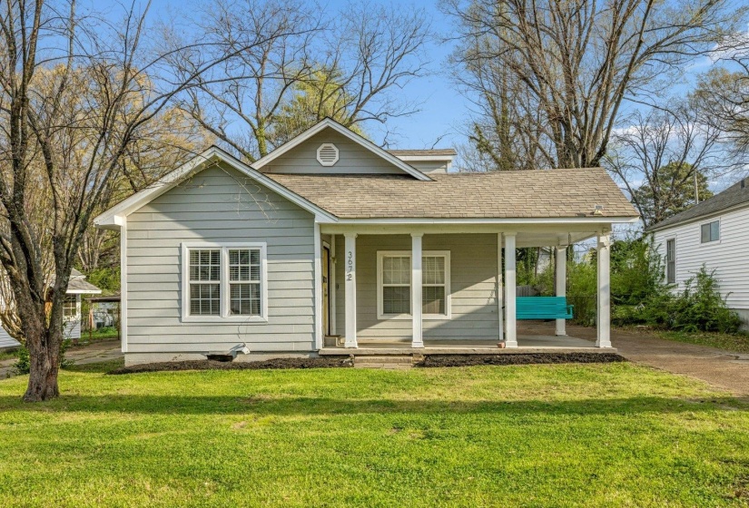 View of front of property featuring covered porch, roof with shingles, and a front yard