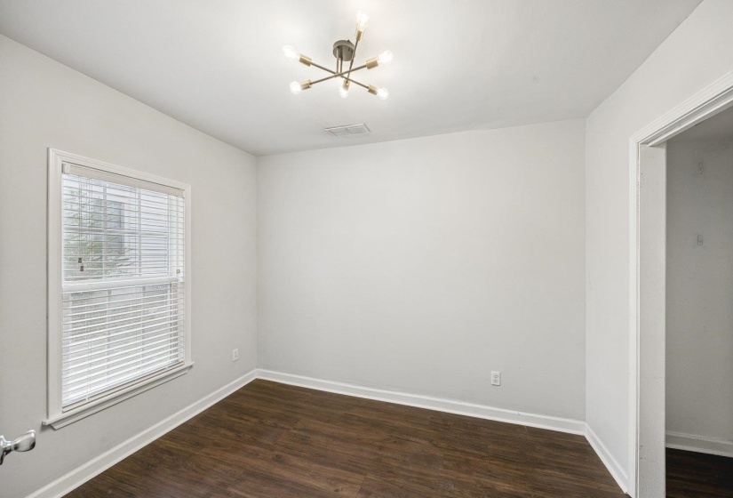 Spare room with dark wood finished floors and a chandelier