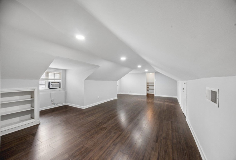Bonus room with built in features, lofted ceiling, dark wood-style floors, and recessed lighting