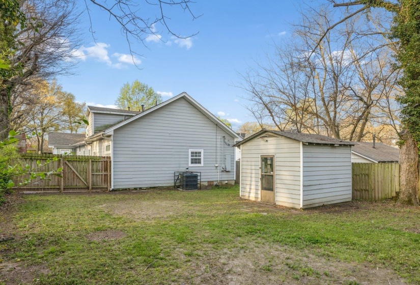 Back of house featuring a fenced backyard, a storage unit, and a gate