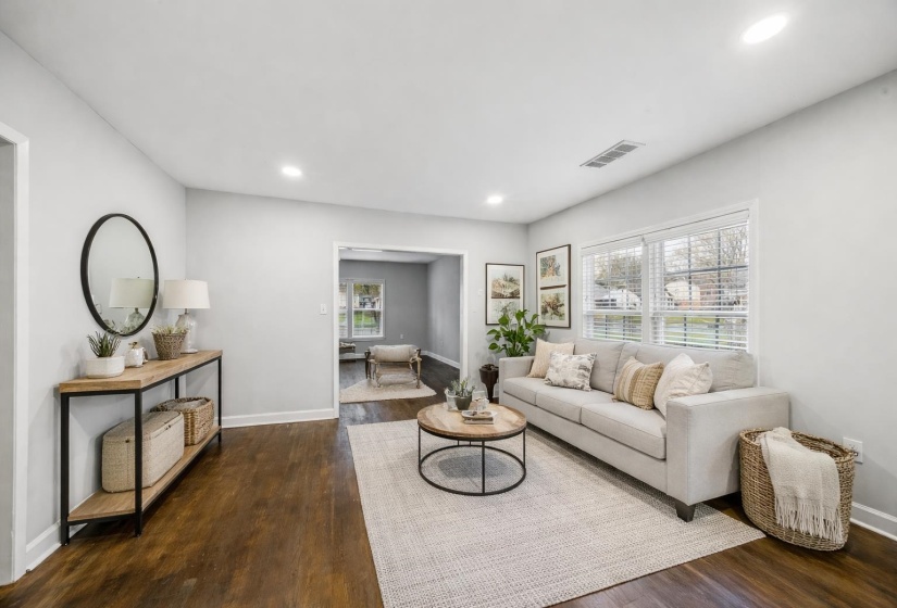 Spacious living area featuring rich wood-finish flooring, recessed lighting, and ample natural light from multiple windows