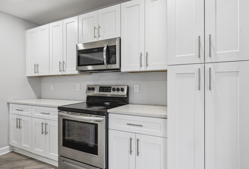 Kitchen featuring stainless steel appliances, white cabinets, and light wood-style flooring
