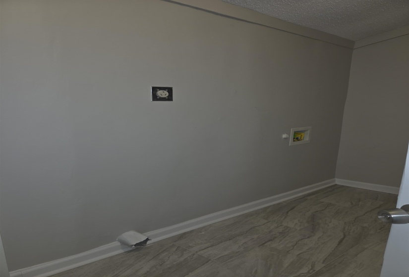 Utility area featuring wood-finish flooring, light gray walls, white baseboards, and a textured ceiling
